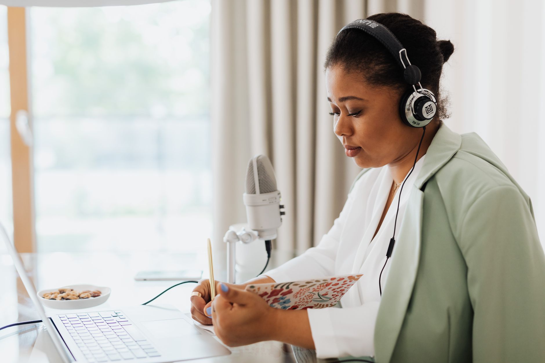 Person listening to UK personal finance podcasts with headphones and notebook on kitchen table